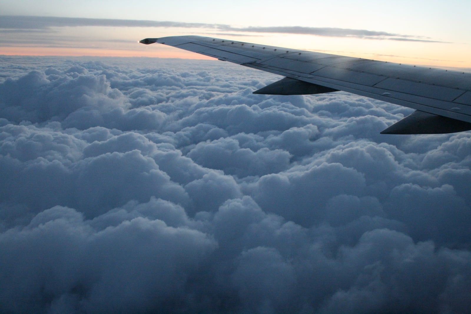 An aircraft wing above clouds at sunset