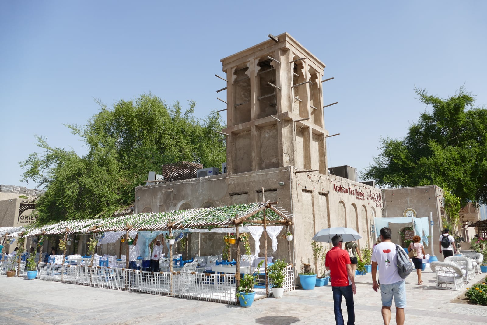 Traditional wind tower rising above a courtyard and pedestrians in Dubai’s Al Fahidi Historical Neighbourhood