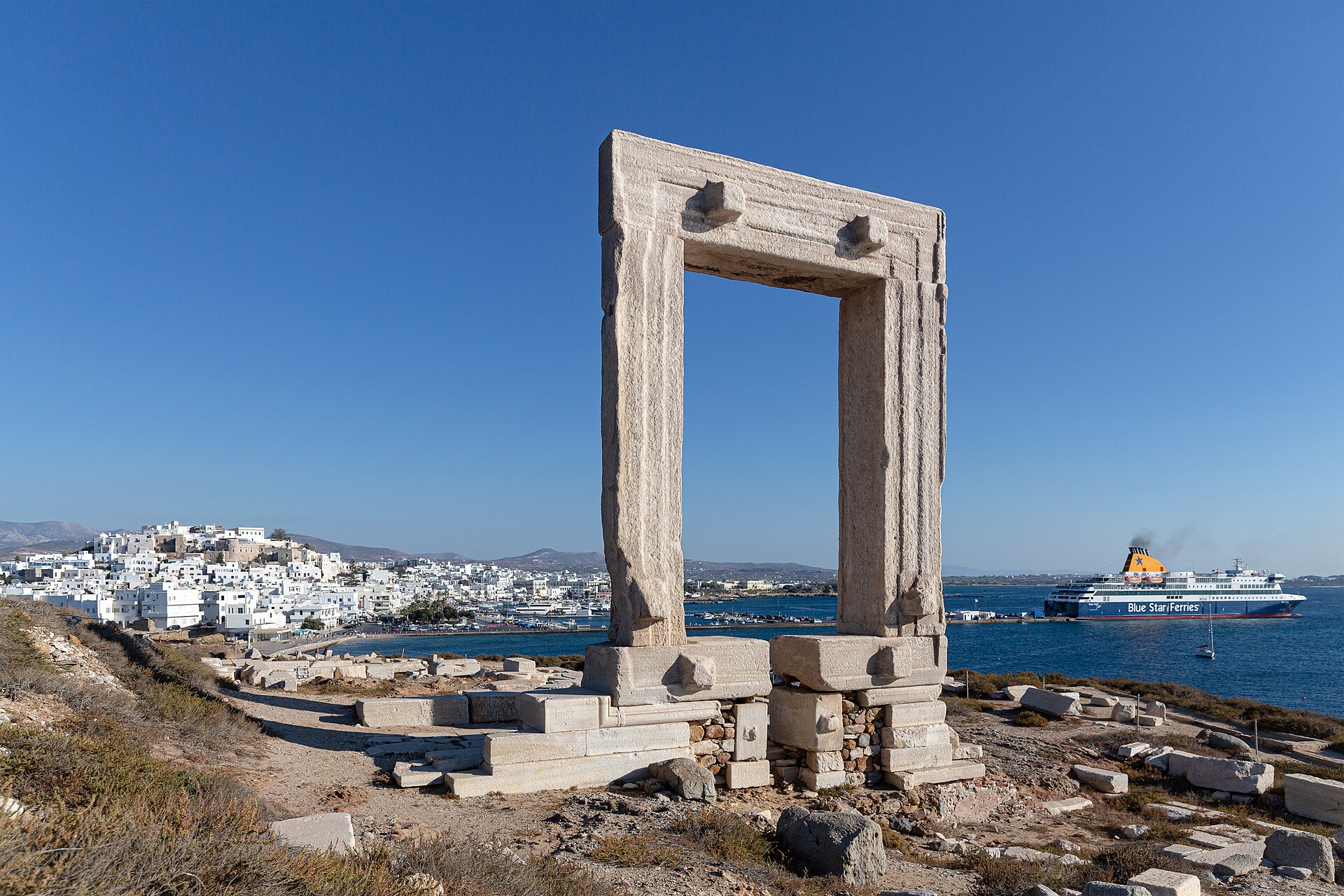 View through the Portara towards Naxos Chora with a Blue Star ferry at the port