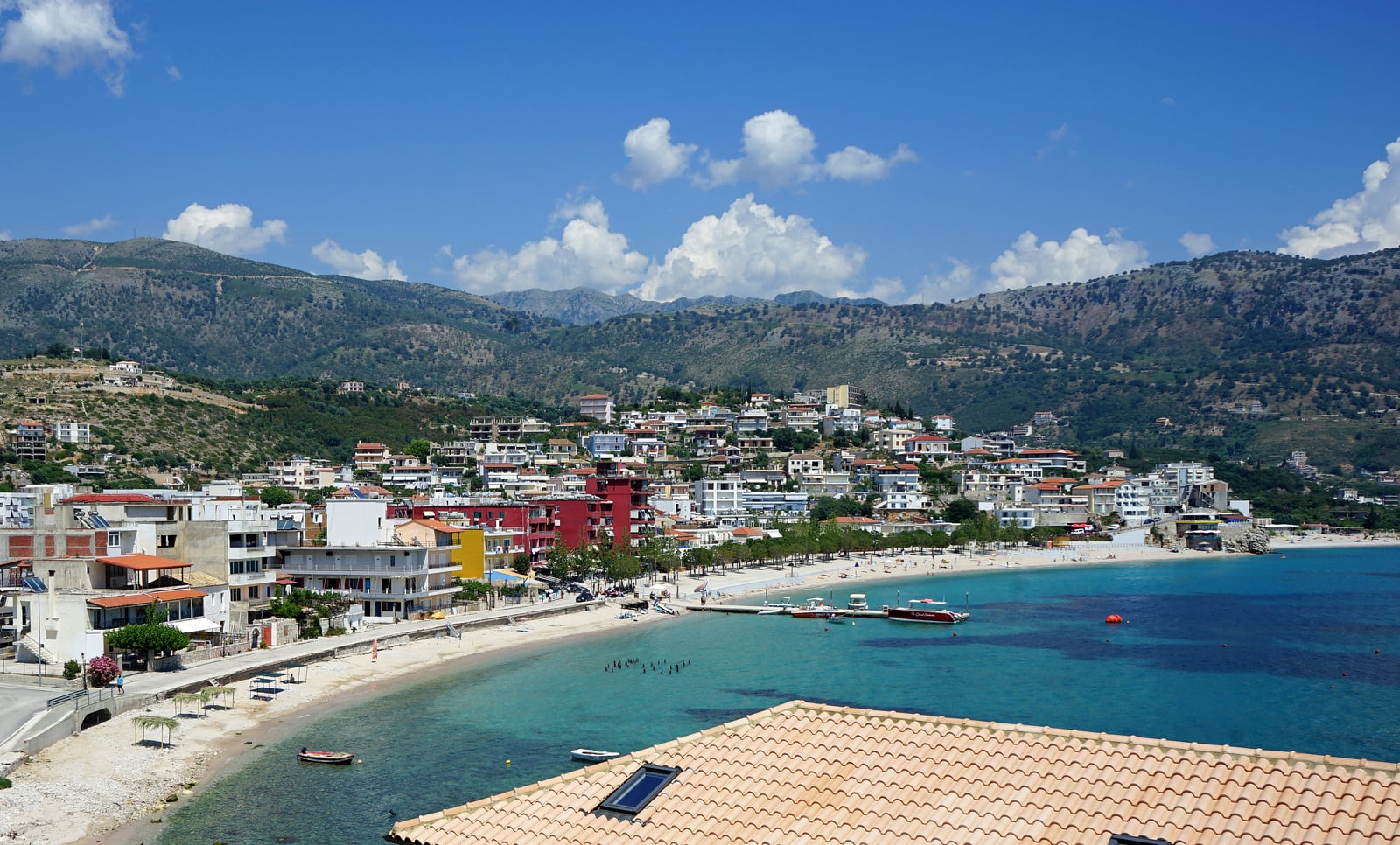 Himarë’s waterfront beach and turquoise bay beneath the hills of Albania’s Ionian coast