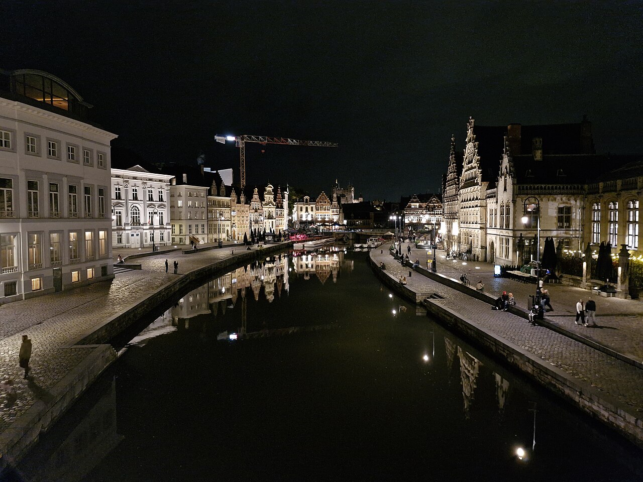 Illuminated historic buildings along Graslei and Korenlei reflected in the water at night in Ghent