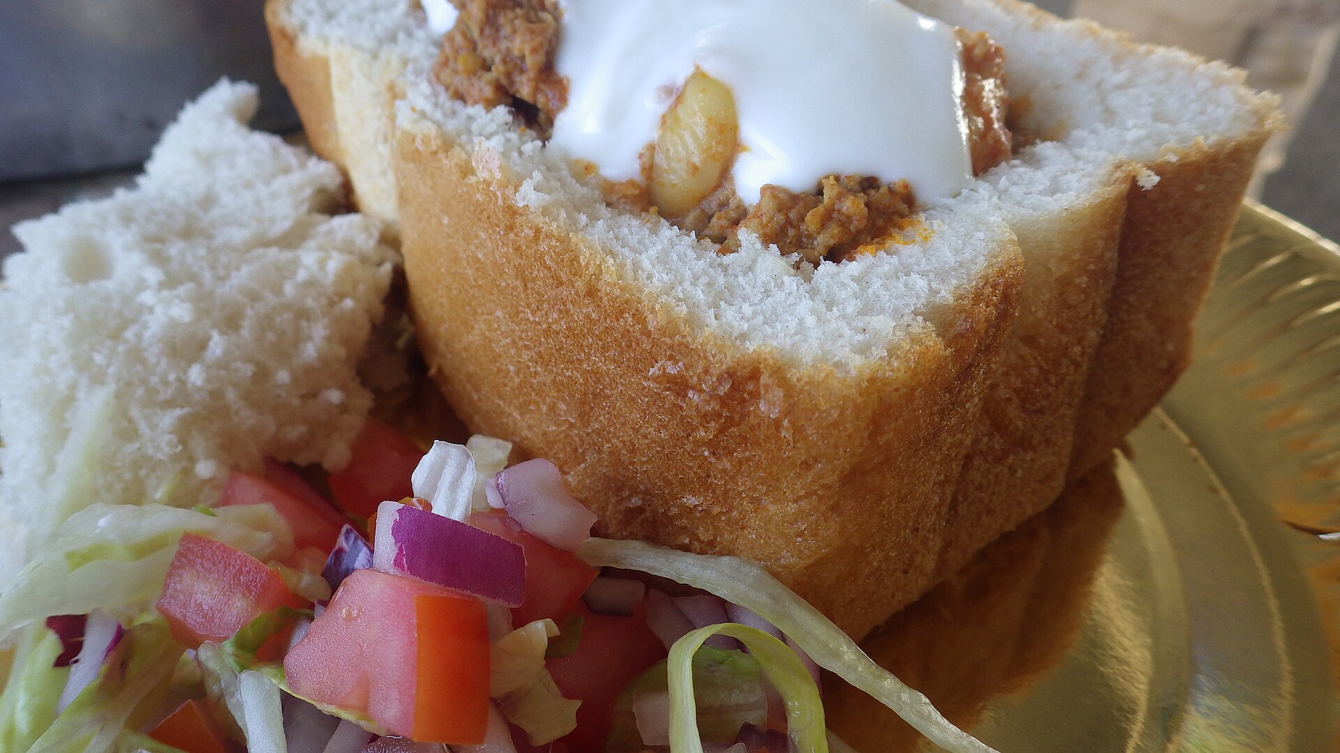 Curry served inside a hollowed white loaf, with salad alongside