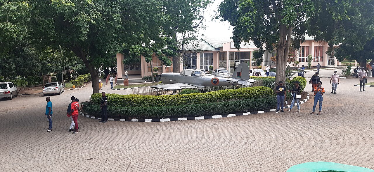 Visitors beside trees and an aircraft display in the forecourt of Livingstone Museum.