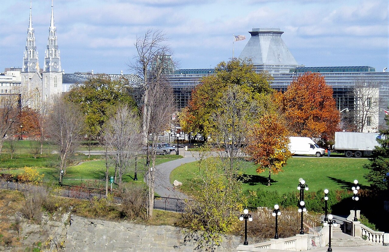 Paths and autumn trees in Ottawa’s Major’s Hill Park, with Notre-Dame Cathedral spires and the United States Embassy in the background.