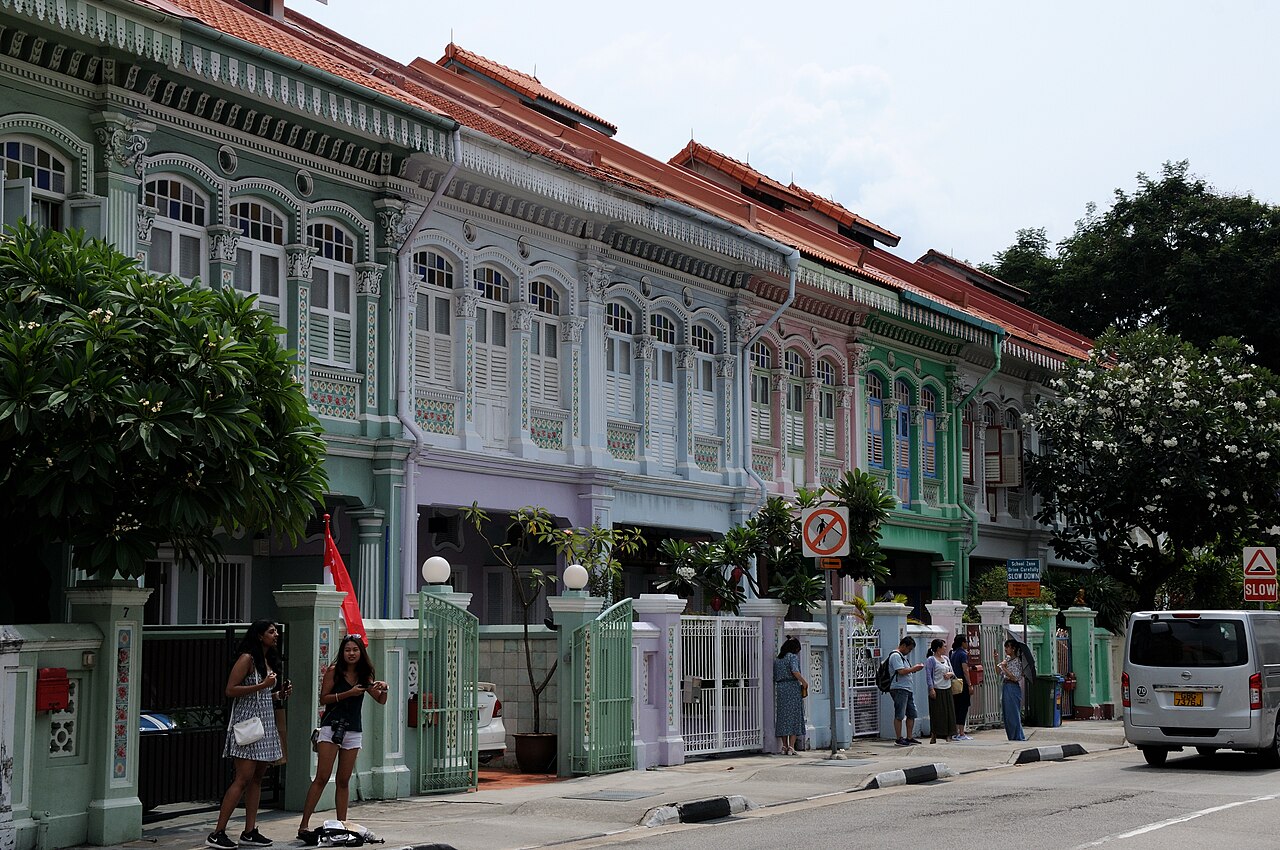Colourful ornamented façades along Koon Seng Road in Singapore, with pedestrians beside the houses.