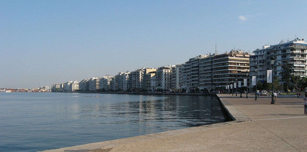 Thessaloniki’s waterfront promenade curving beside the sea, with a long row of city buildings beyond.